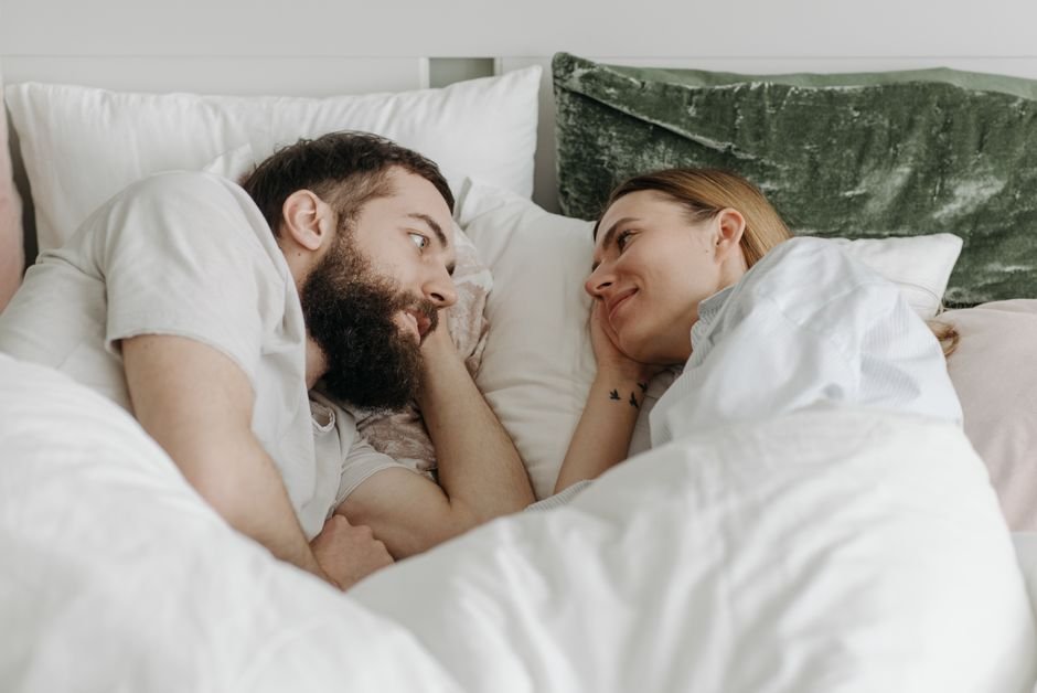 Couple complice allongé dans un lit, se regardant tendrement