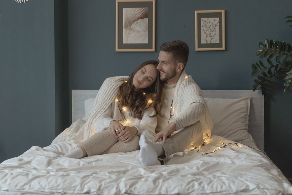 Couple enlacé sous un plaid au lit, ambiance cosy