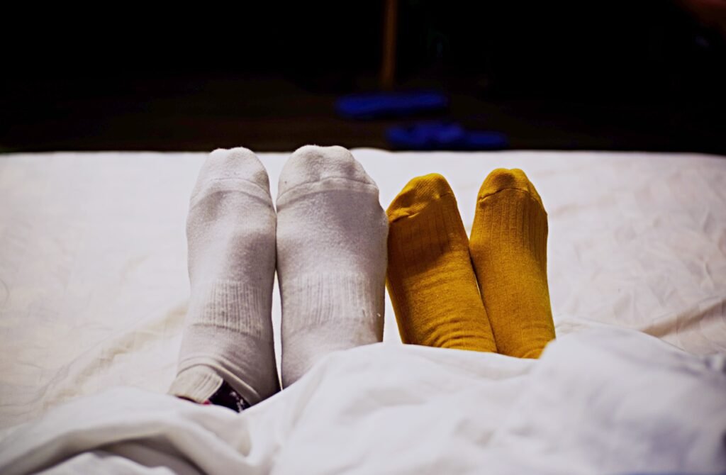 Deux paires de pieds côte à côte dans un lit