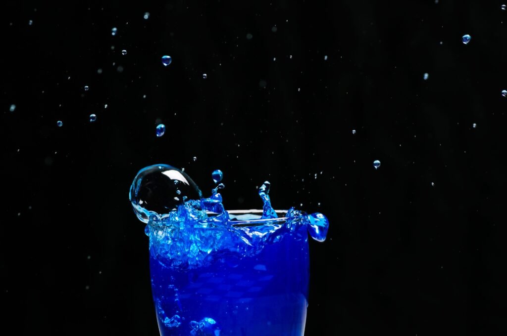 Éclaboussure de liquide bleu jaillissant d'un verre sur fond noir