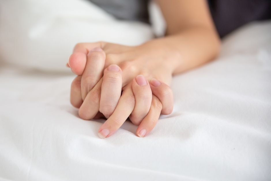 Mains d’un couple entrelacées agrippant un drap blanc