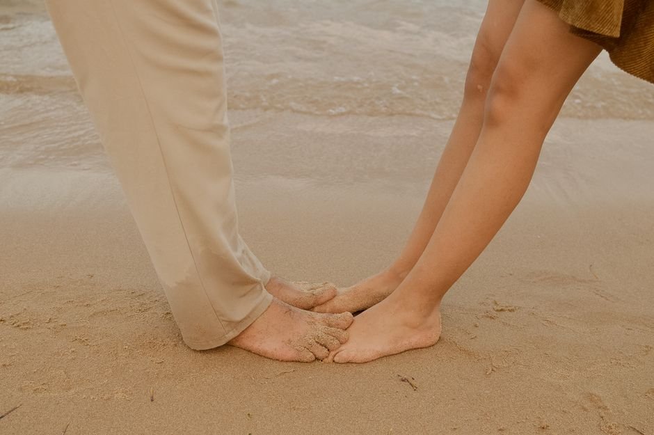 Pieds nus d'un couple se touchant sur le sable d'une plage