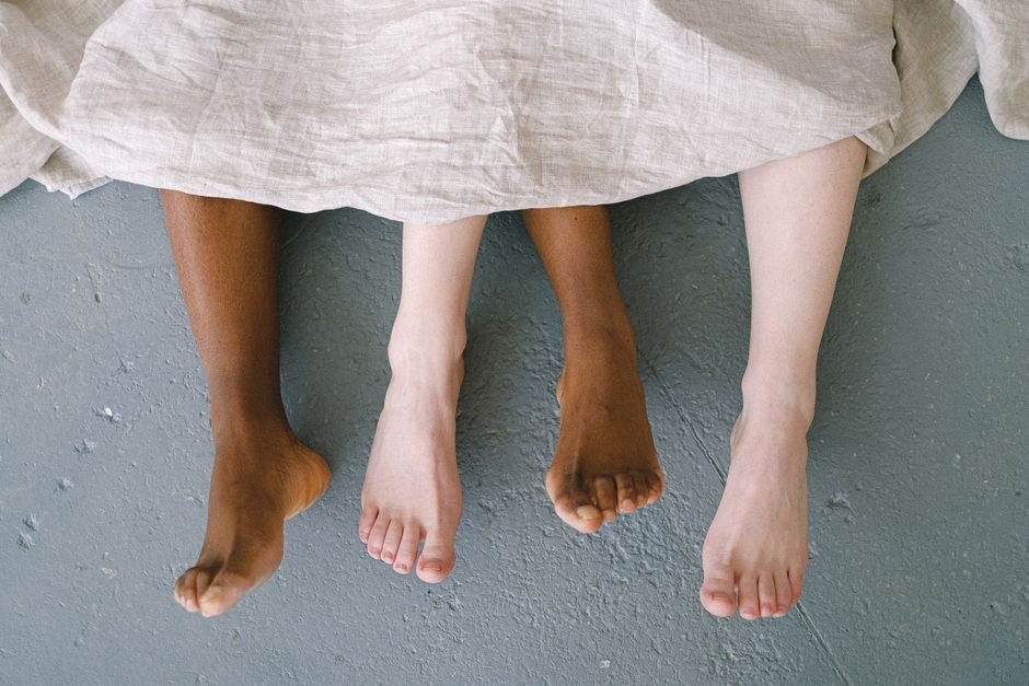 Pieds nus de plusieurs personnes dépassant d'un drap de lit