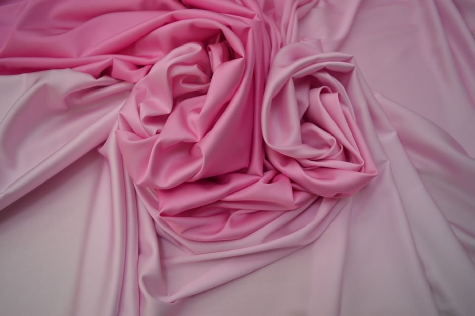 Tissu de satin rose enroulé, image sensuelle et abstraite